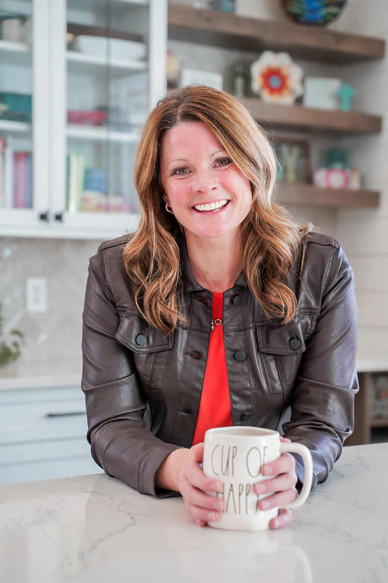 Angela Gaffney smiling in her kitchen while holding a coffee cup.